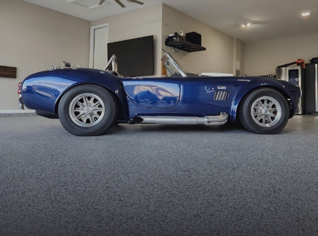 curvy white sports car parked on poly flake flooring