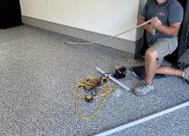 worker kneeling in floor during polyaspartic flooring installation